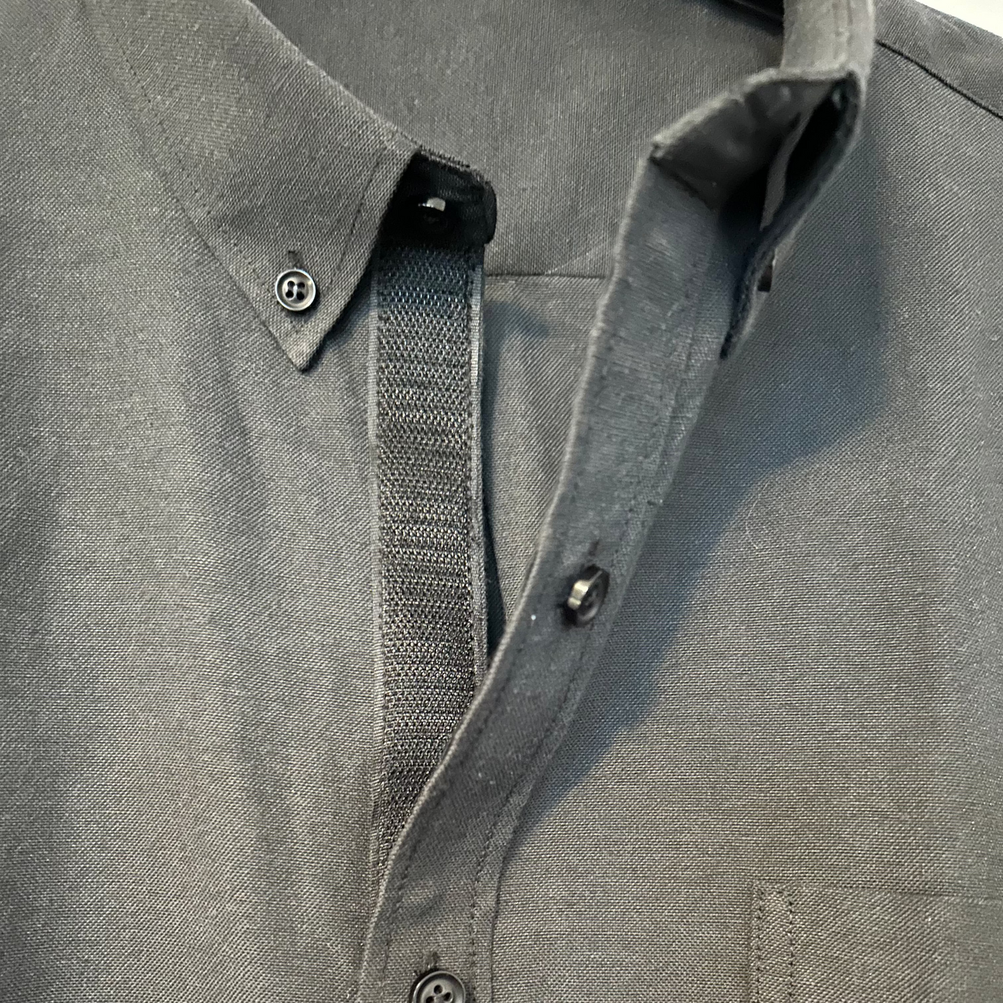 Close-up of a gray shirt with buttons and a strap.