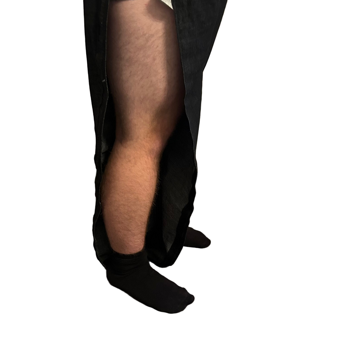 Person wearing black pants and socks on a wooden floor with a curtain in the background