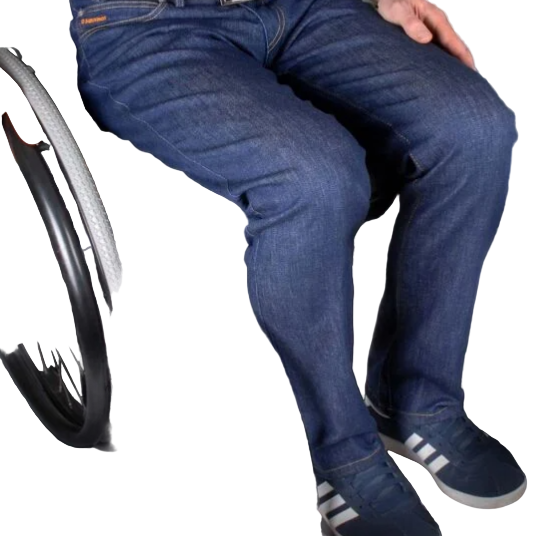Person in a wheelchair wearing blue jeans and Adidas shoes on a dark surface.