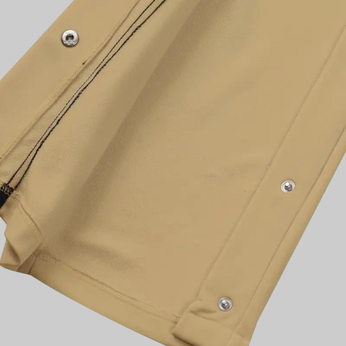 Close-up of beige pants with button details on a white background