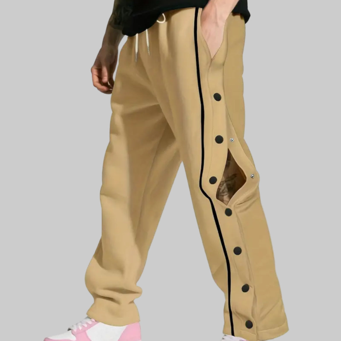 Beige pants with black buttons and side stripes worn by a person on a white background